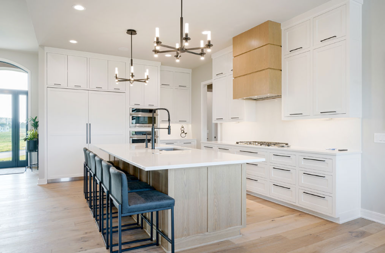 Modern white kitchen with island, wood accents, and bar stools.
