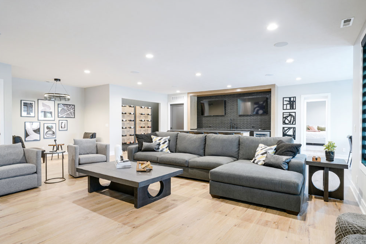 Modern living room with gray furniture, bar, and artwork.