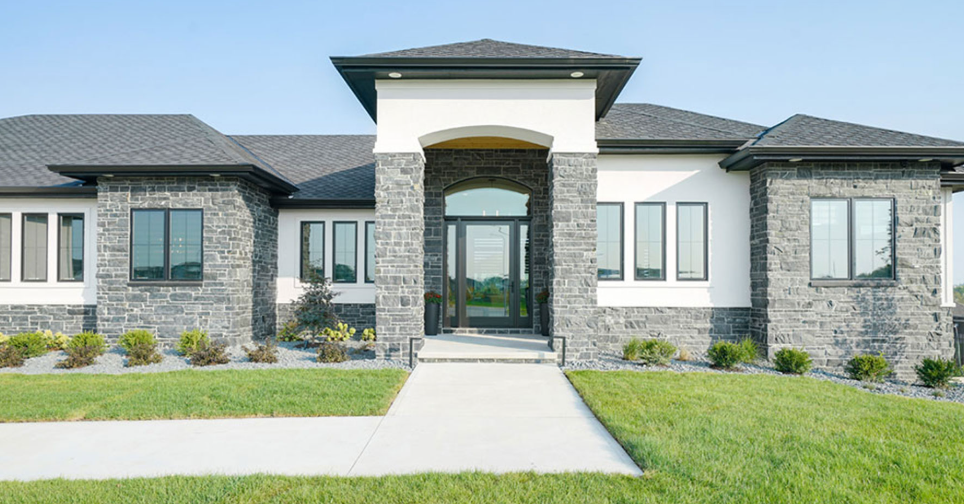 Modern single-story house with gray stone accents, white walls, and a welcoming entrance.