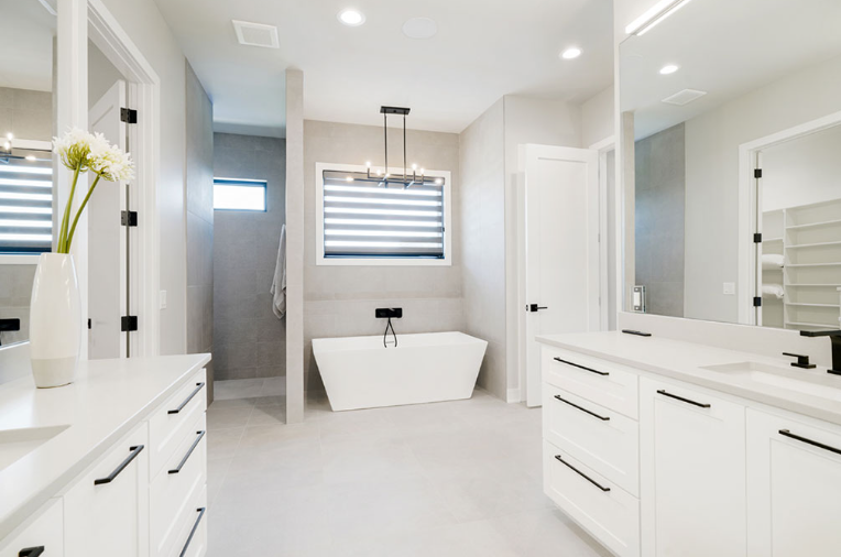 Modern white bathroom with double vanity, freestanding tub, and shower.