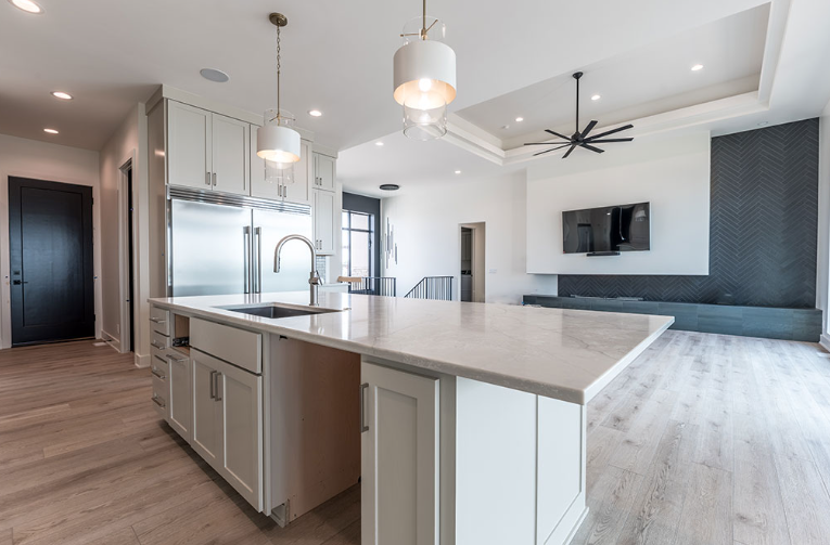 Modern kitchen with white cabinets, large island, and light wood floors.