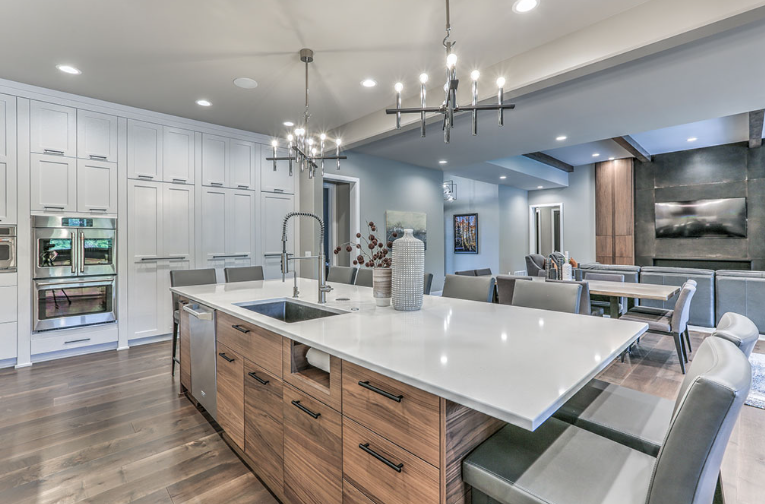 Modern kitchen with white cabinets, wood island, and open dining area.
