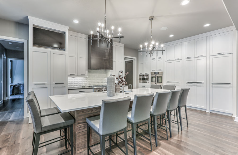 Spacious modern kitchen with white cabinetry, large island with seating, and hardwood floors.