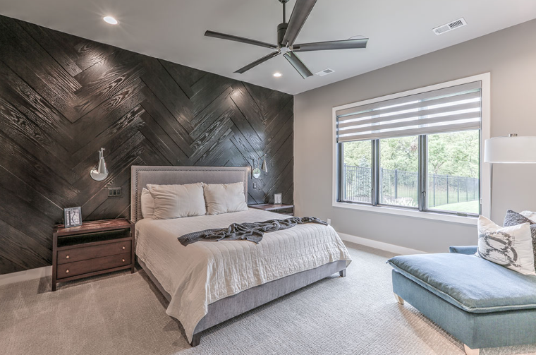 Bedroom with dark wood accent wall, bed, window, and chaise lounge.