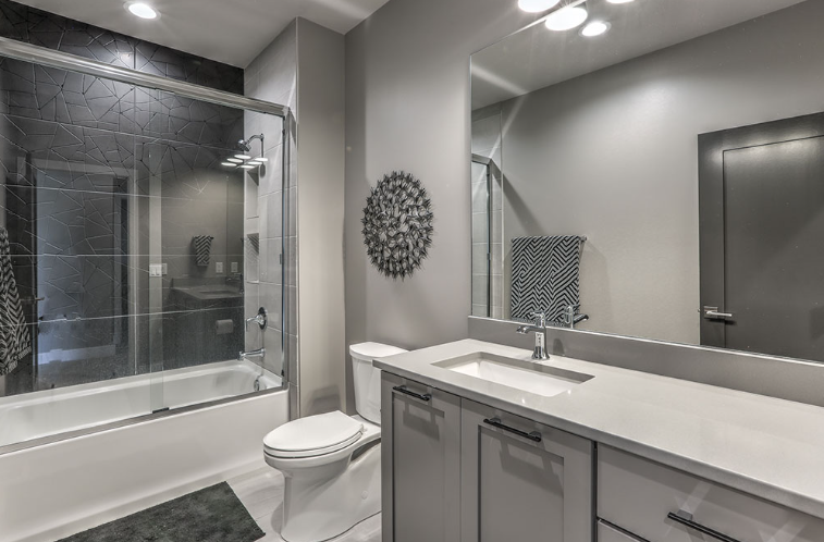 Modern bathroom with gray walls, white countertop, and glass shower enclosure.