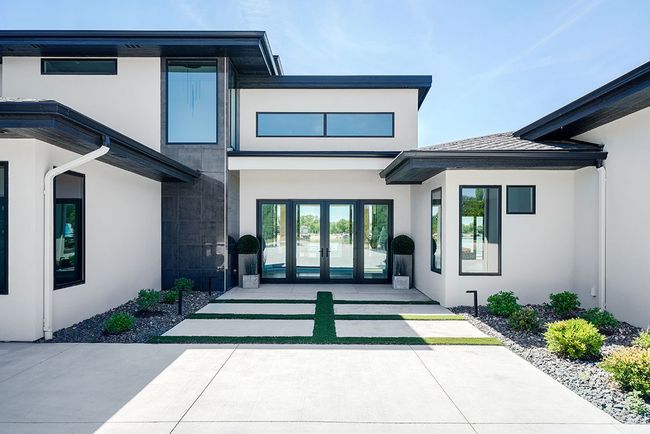 Modern white house with dark trim, double doors, and rectangular windows.