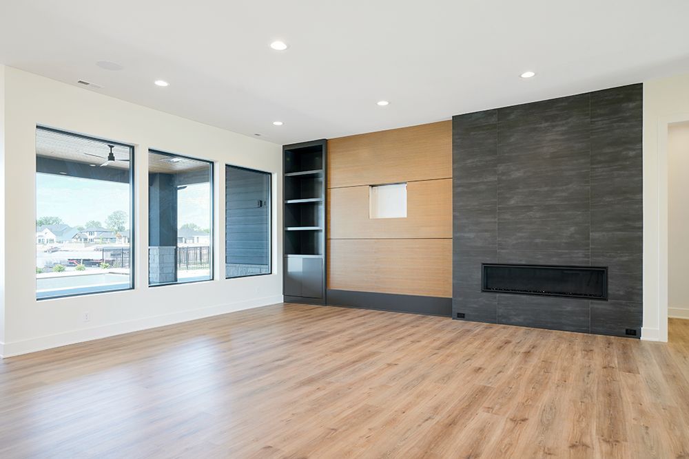 Empty modern living room with large windows and fireplace.