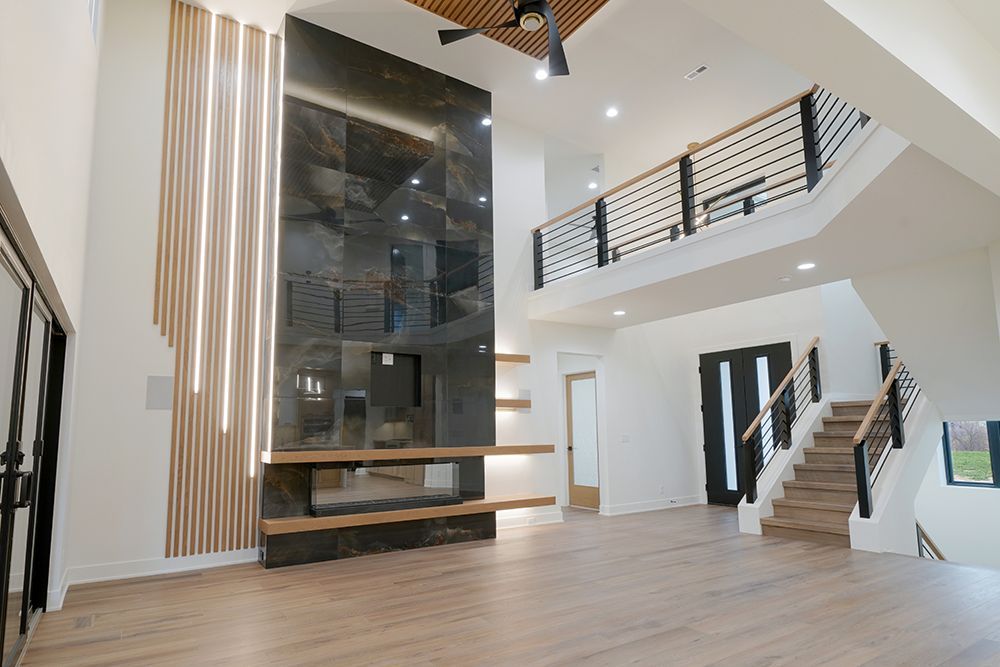 Modern home interior with high ceilings, fireplace, staircase, and balcony.