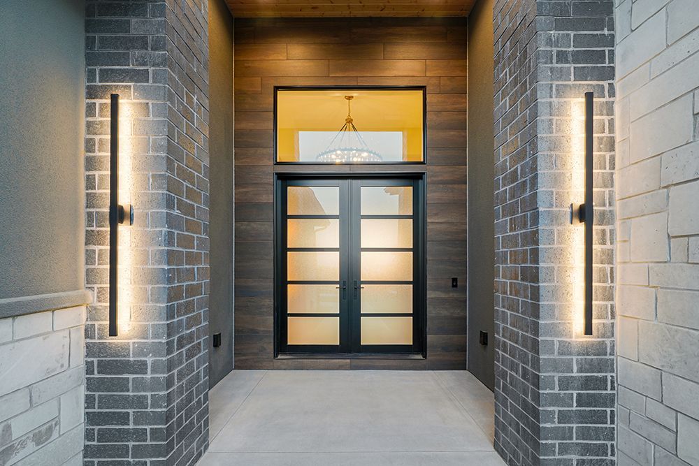Entryway with modern black door, sidelights, and vertical LED sconces on brick columns.
