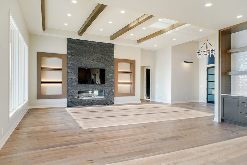 Spacious living room with stone fireplace, built-in shelves, and light wood flooring.