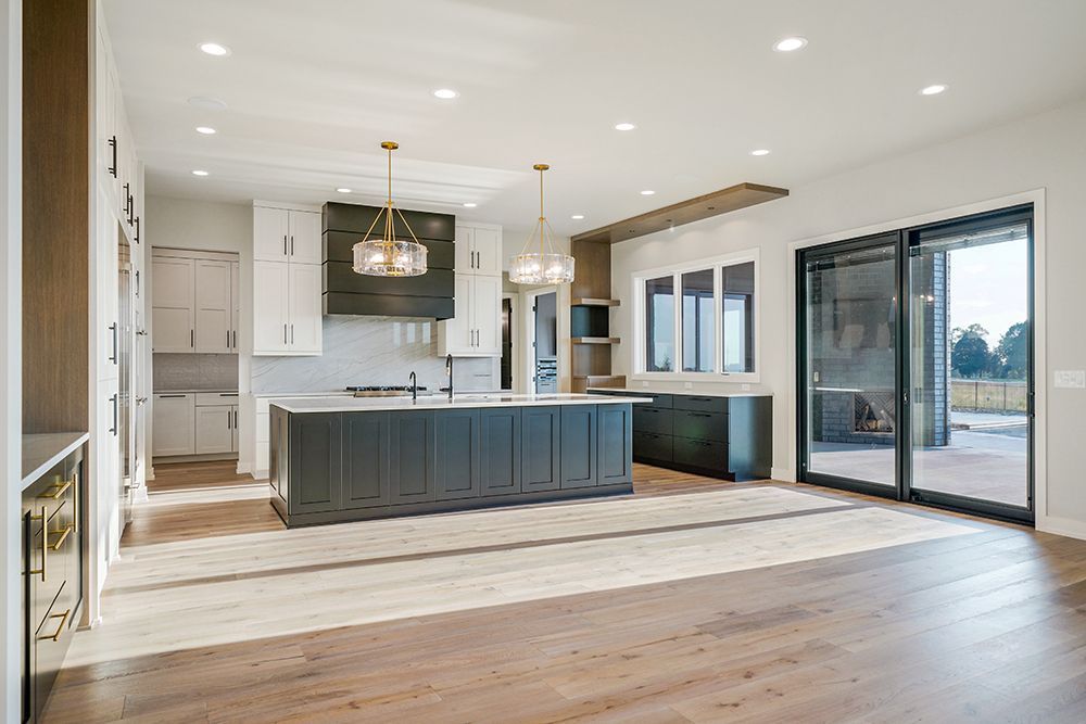 Modern kitchen with dark island, white cabinets, and large sliding glass doors.