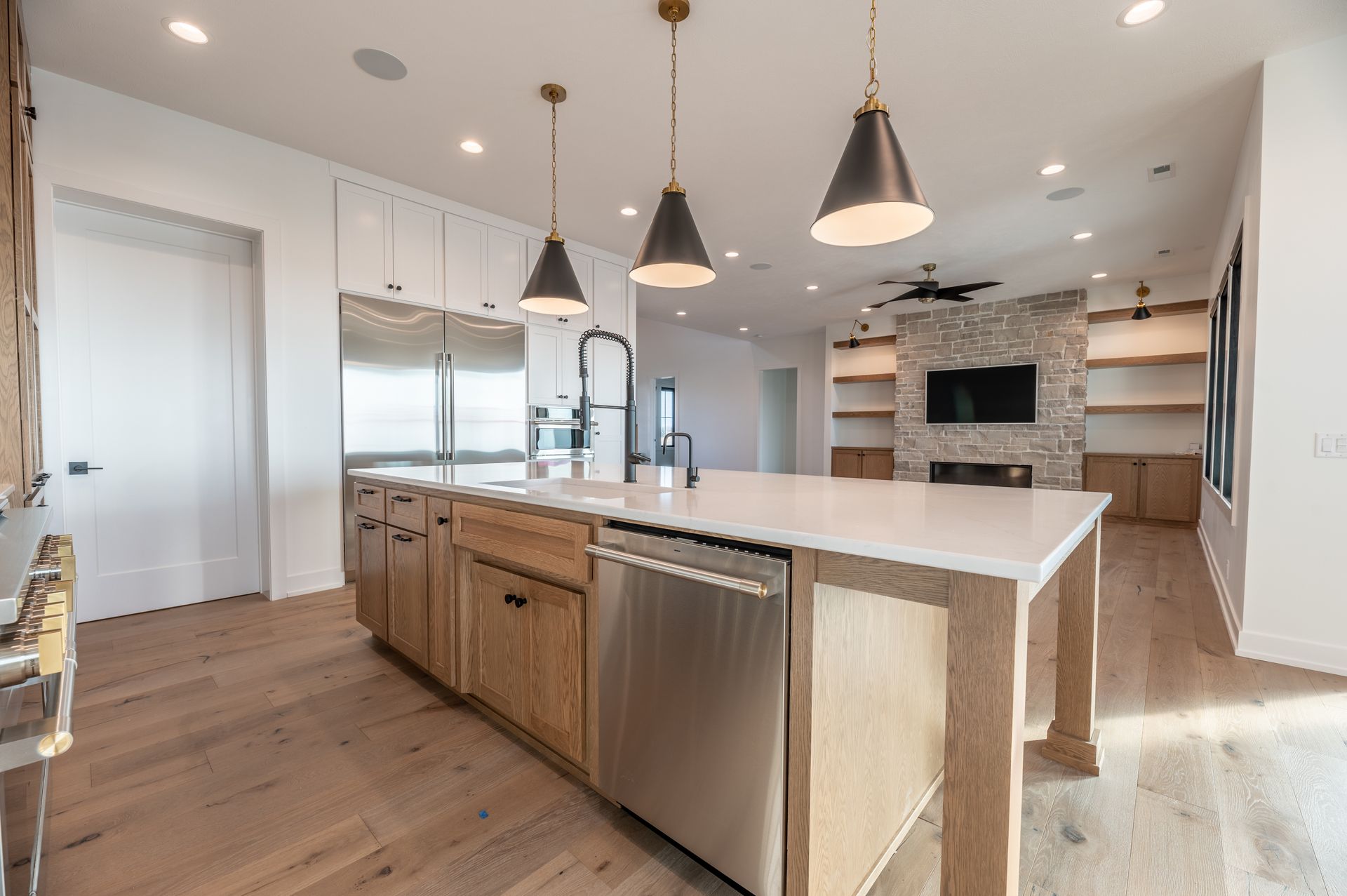 Modern kitchen with wooden floors, island, stainless steel appliances, and pendant lights.