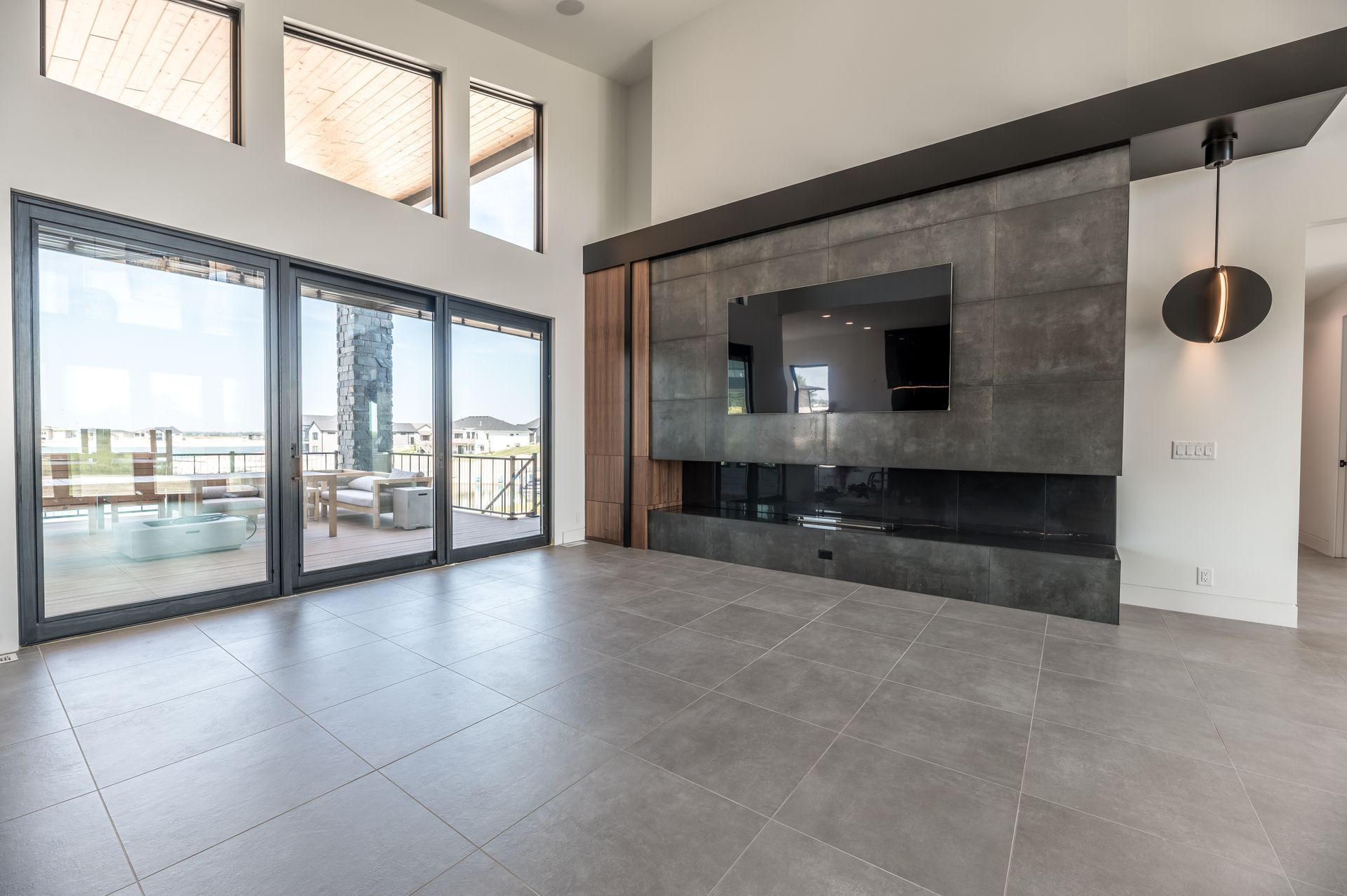 Modern living room with large windows, fireplace, TV, and gray tile floor.