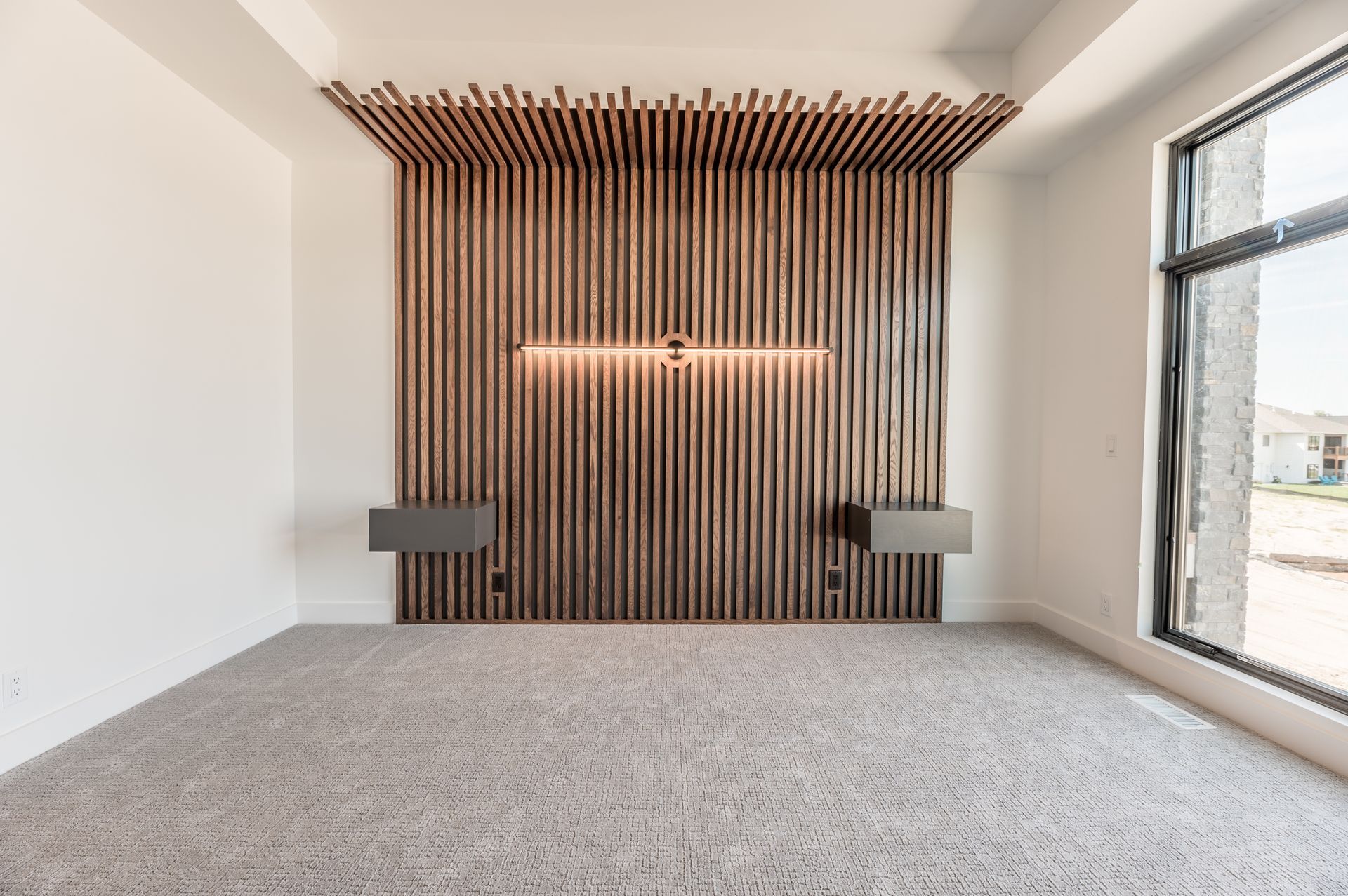 Bedroom with vertical wooden accent wall and floating nightstands; large window to the right.