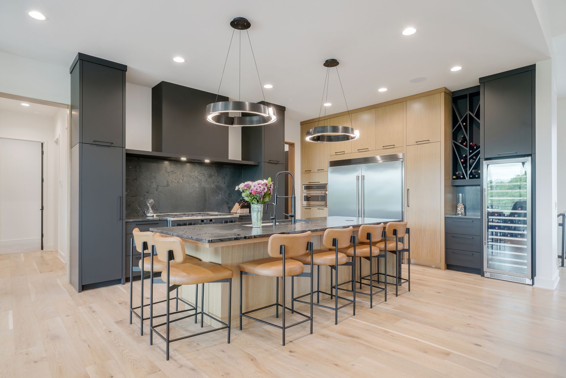 Modern kitchen with a large island, stainless steel appliances, and dark cabinets.