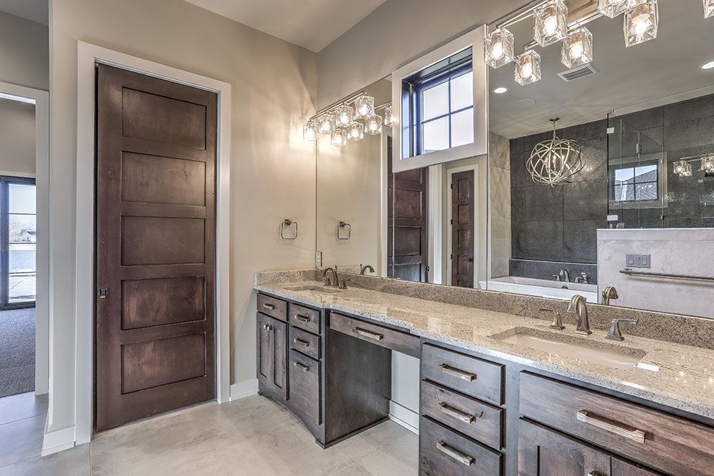 Bathroom with double vanity, dark cabinets, granite countertop, and large mirror.