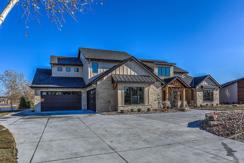 Modern two-story house with a long concrete driveway, blue sky, and brown garage door.