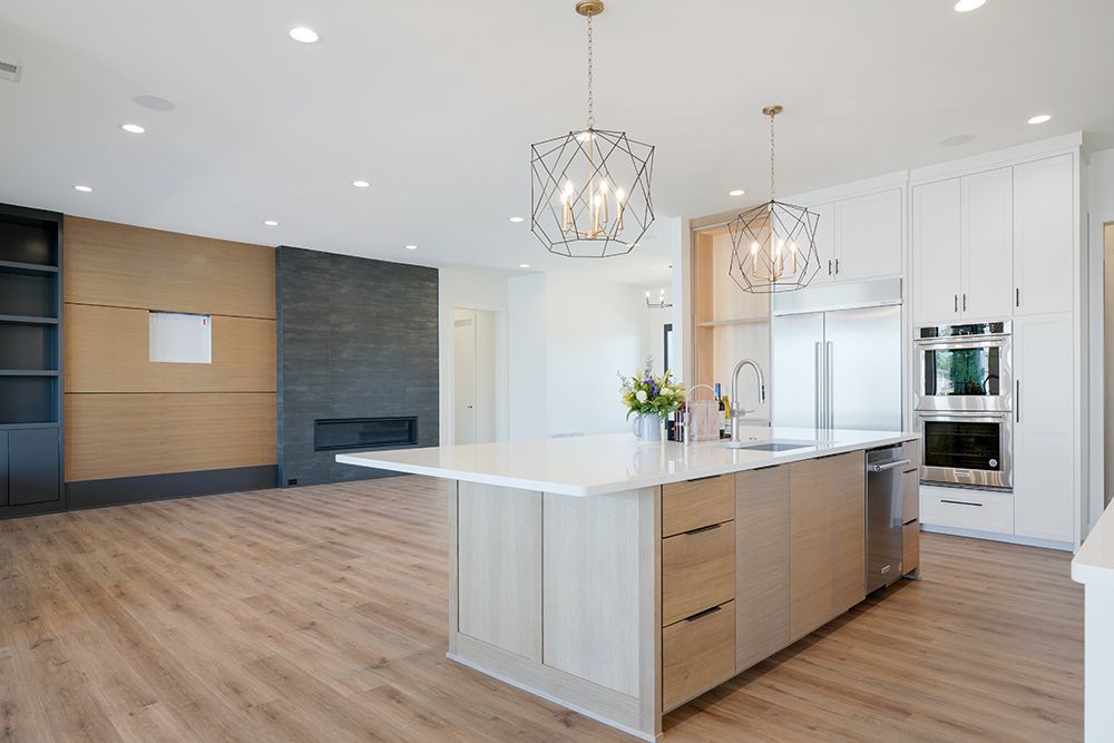 Modern kitchen with island, white cabinetry, stainless steel appliances, and wood flooring.