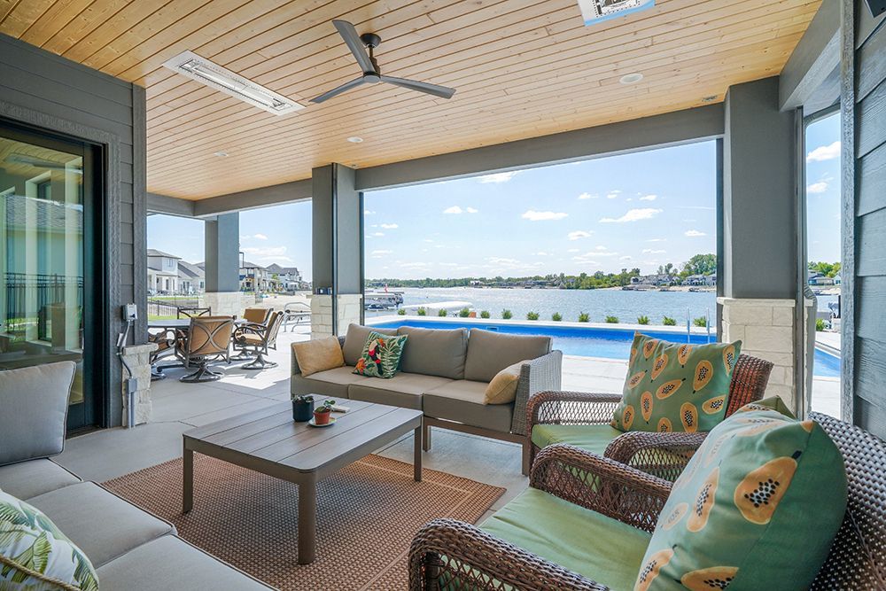 Outdoor patio overlooking a pool and lake with seating, a ceiling fan, and a light.