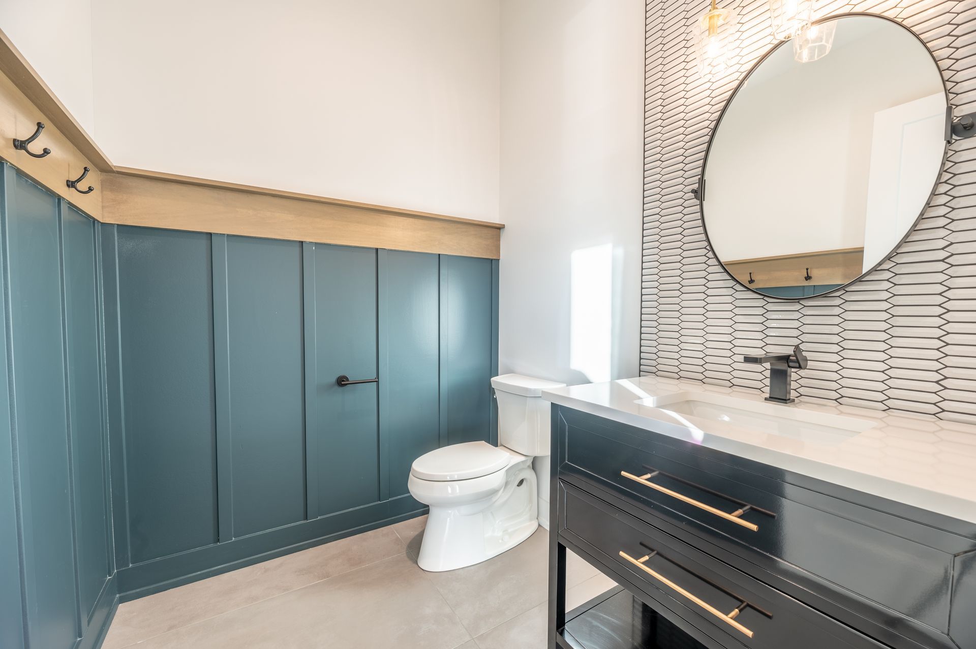 Blue paneled bathroom with white toilet, black vanity, and decorative tile.