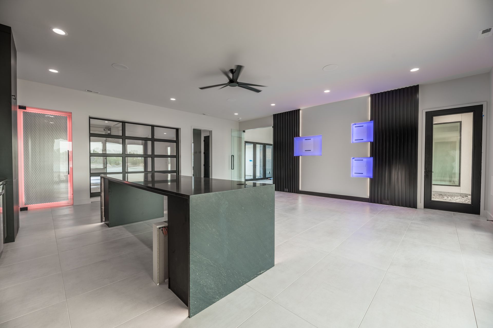 Modern kitchen with large island, glass wall, and gray walls, with decorative blue squares.