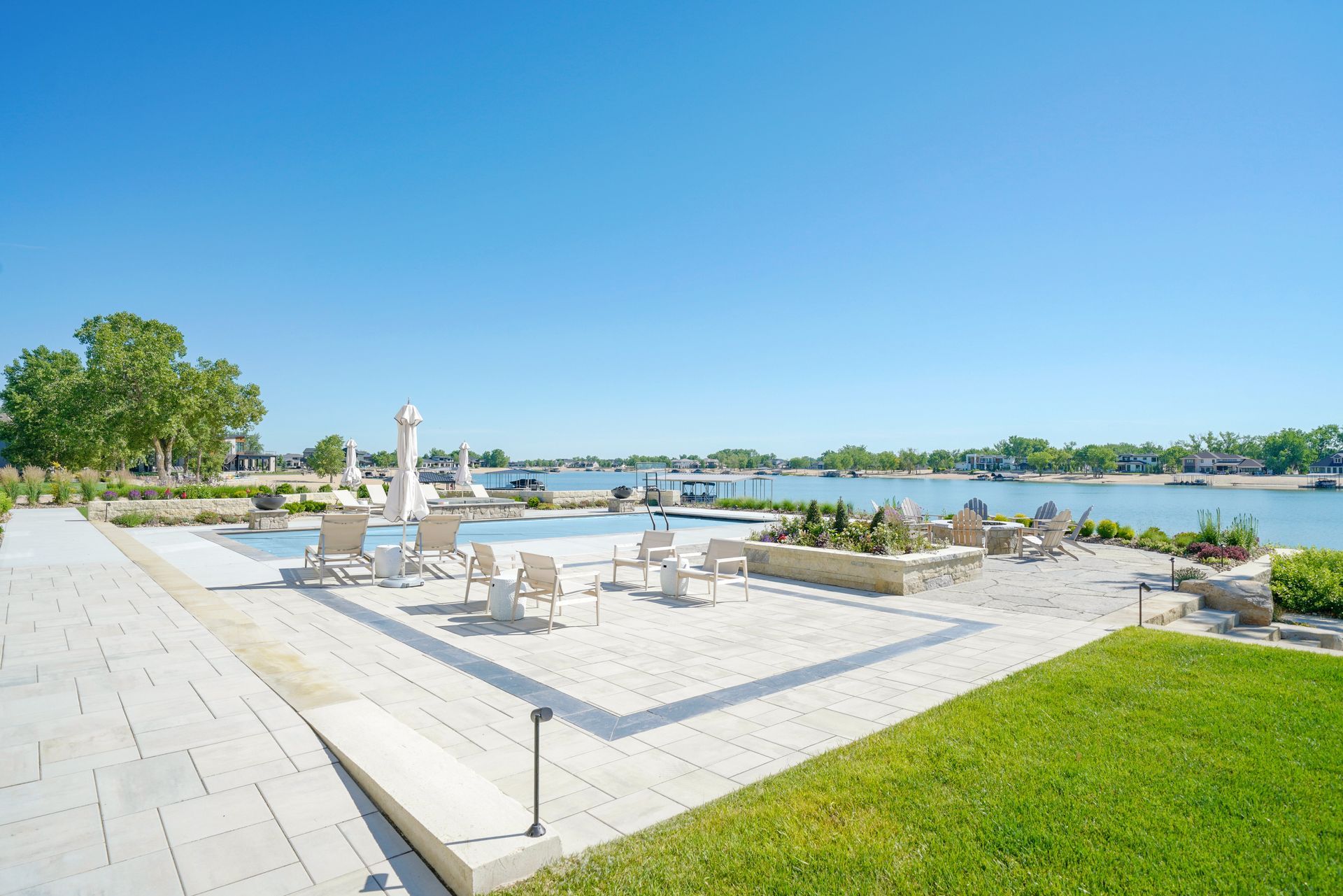 Poolside area with chairs, overlooking a body of water and blue sky.