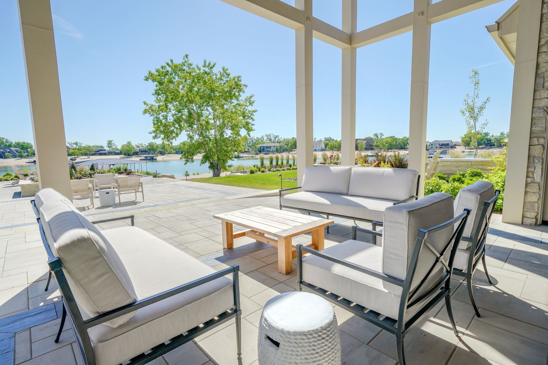 Patio with modern gray furniture overlooking a lake on a sunny day.