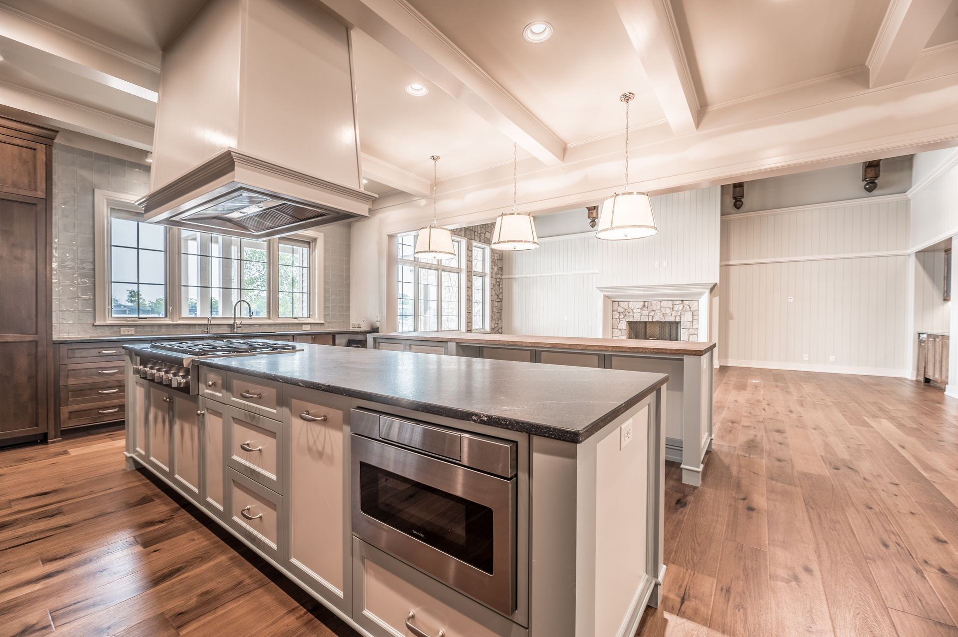 Spacious kitchen with large island, stainless steel appliances, light blue cabinets, and hardwood floors.