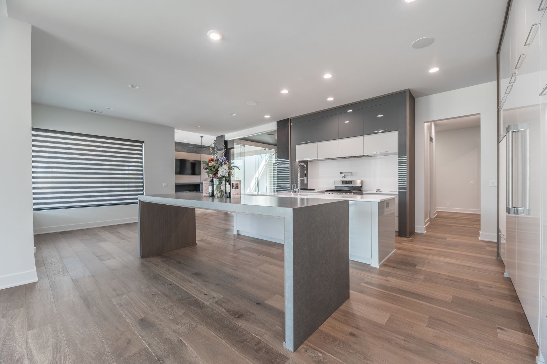 Modern kitchen with large island, light wood floors, and minimalist gray and white cabinetry.
