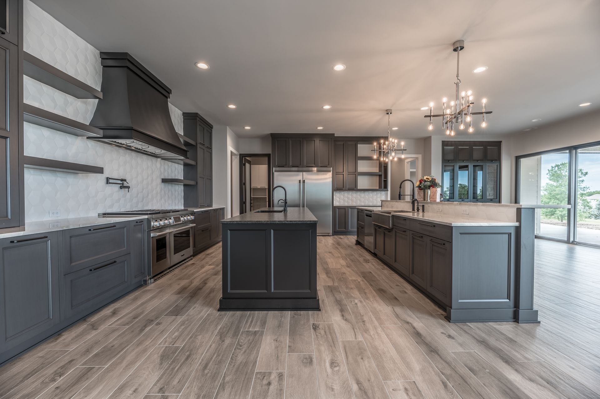 Modern kitchen with gray cabinets, stainless steel appliances, and two islands.