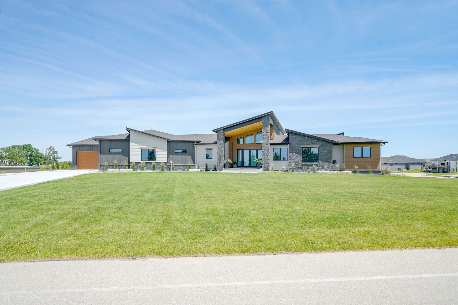 Modern single-story home with a grassy lawn on a sunny day.