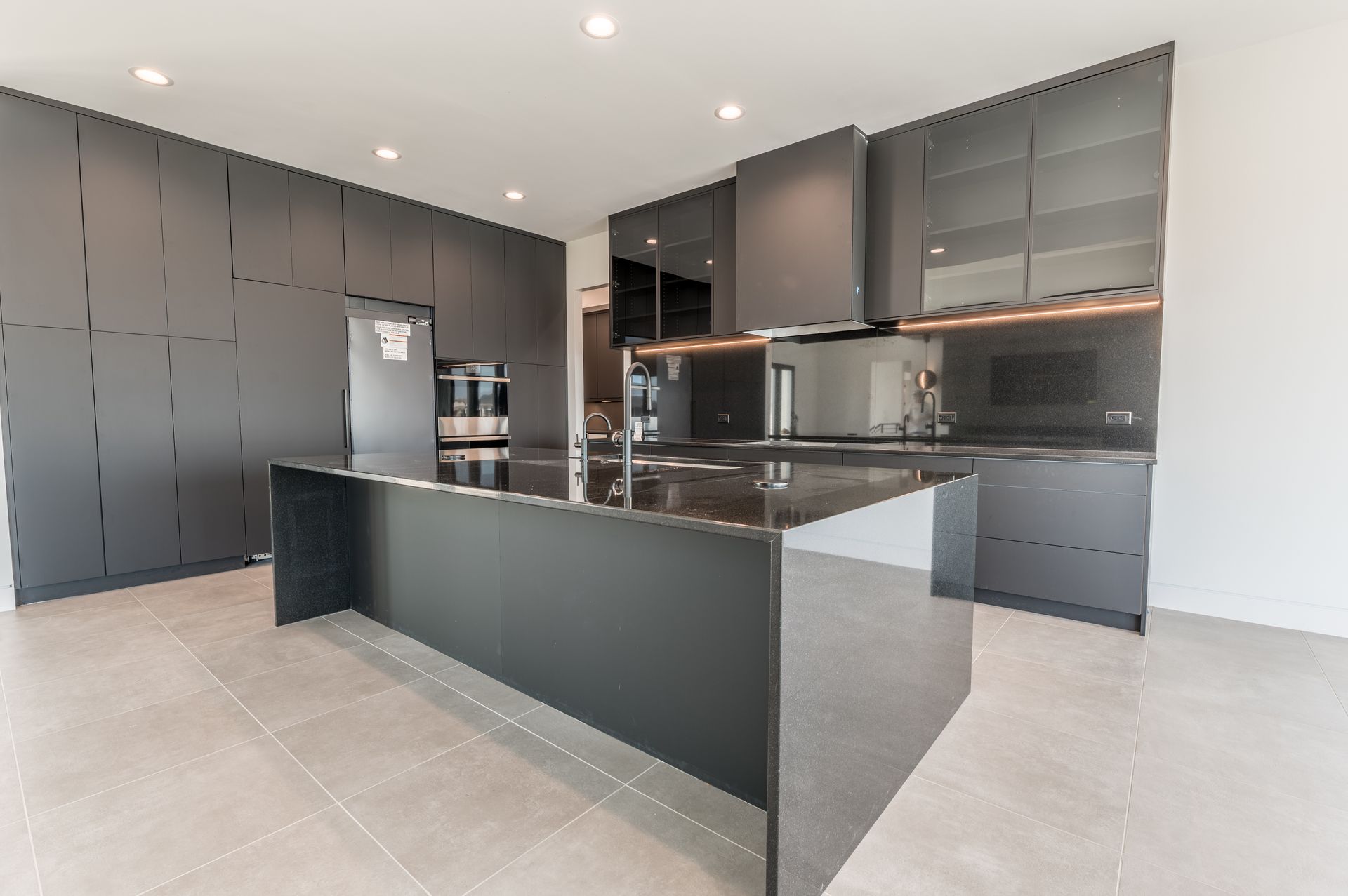 Modern gray kitchen with island, cabinets, and appliances.