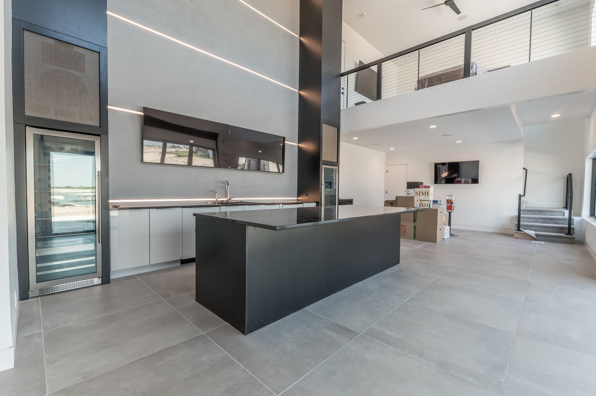 Modern kitchen with black island, white cabinets, and a loft area above.