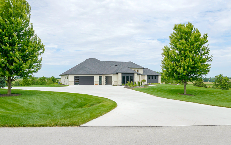 A modern house with a long driveway on a sunny day.