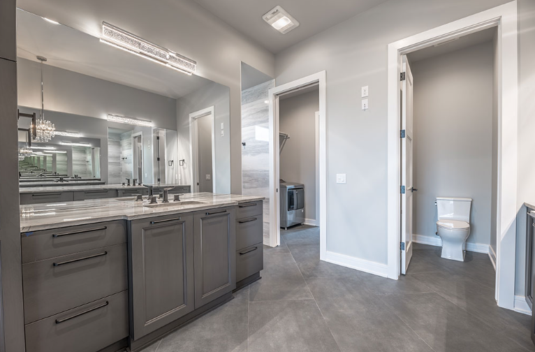 Gray bathroom with vanity, toilet, and laundry room access.