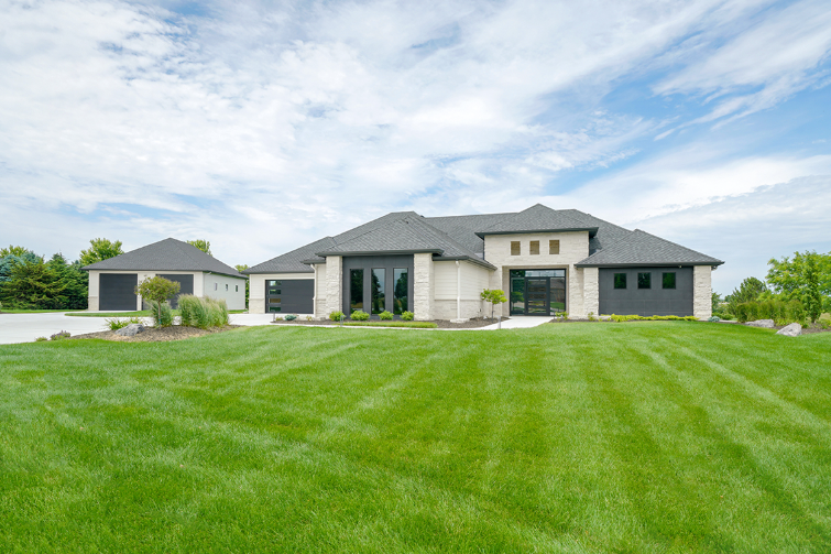 A modern, single-story house with a green lawn and blue sky.