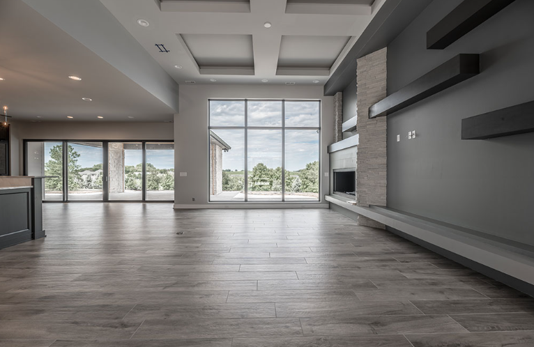 Modern living room with large windows, grey walls, and wooden floors.