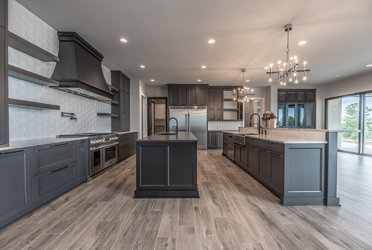 Modern kitchen with gray cabinets, wooden floors, and two islands.