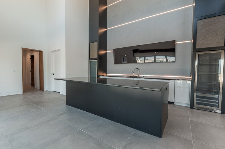 Modern kitchen with black island, gray countertops, and high ceilings.