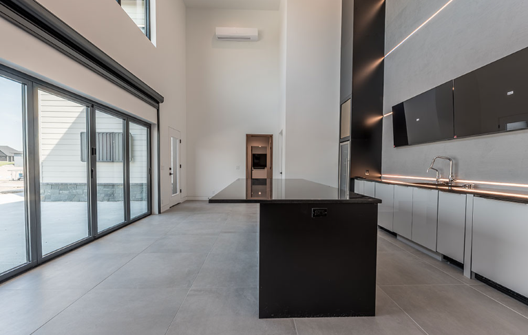 Modern kitchen interior with large island and sleek black cabinets.