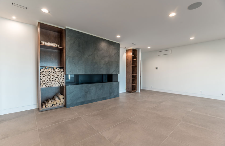 Modern living room with fireplace, built-in shelving, and light-colored flooring.