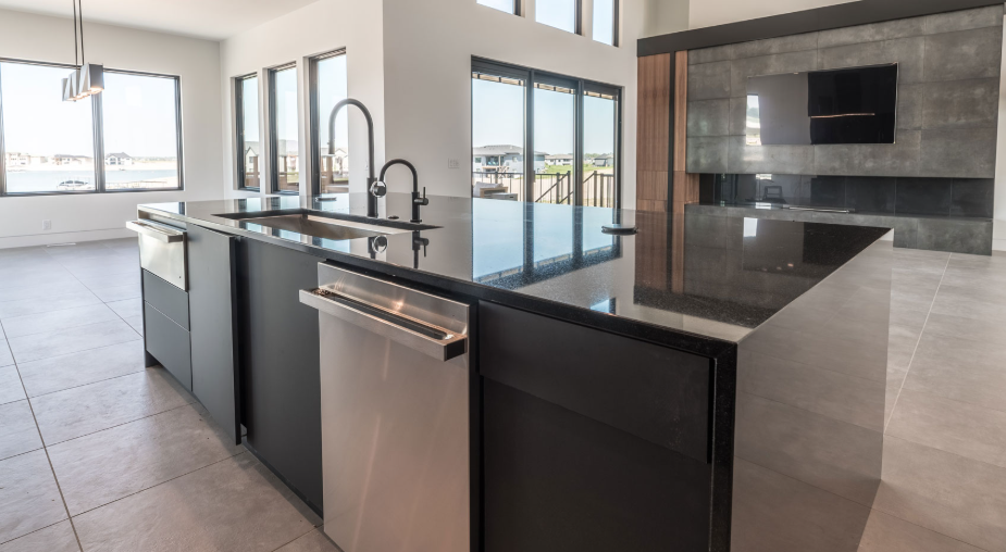Modern kitchen with black island, granite countertop, stainless steel appliances, and large windows.