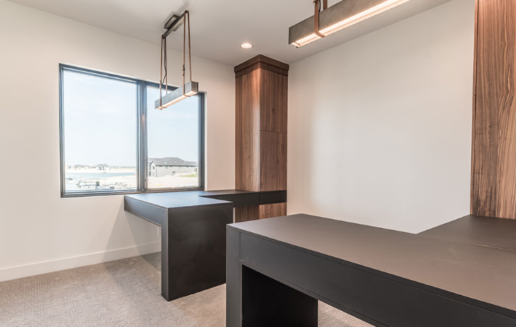 Modern office with dark desks, large window, and neutral walls.