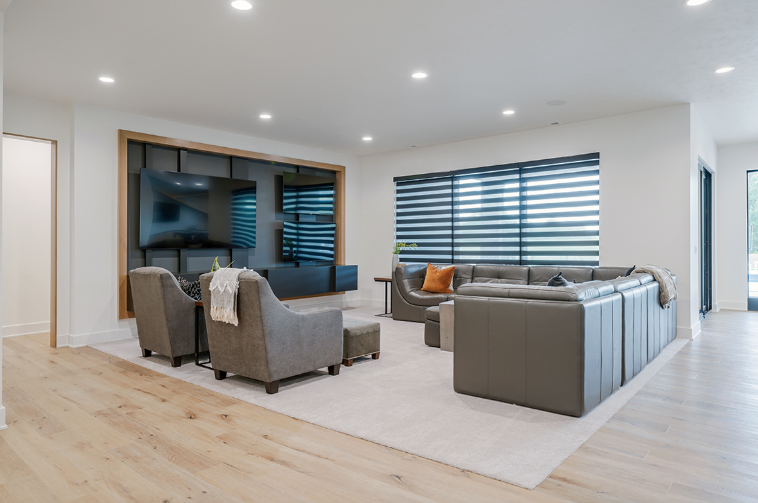 Modern living room with gray furniture, large TV, and light wood floors.