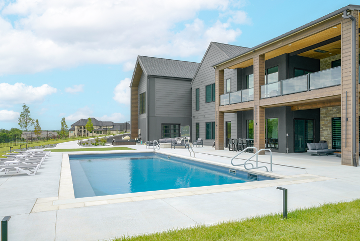 Modern house with pool and outdoor seating. Blue sky with clouds.