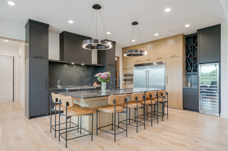 Modern kitchen with black cabinetry, wood island, and leather bar stools.