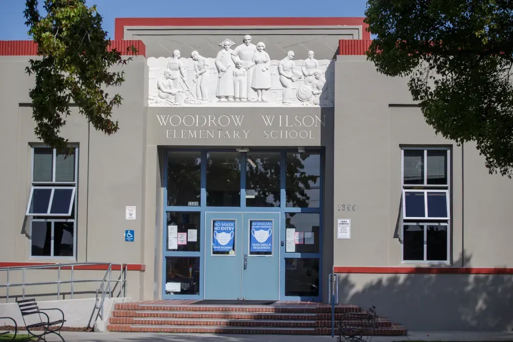 Woodrow Wilson Elementary School entrance with relief sculpture, blue doors, windows, and brick steps.