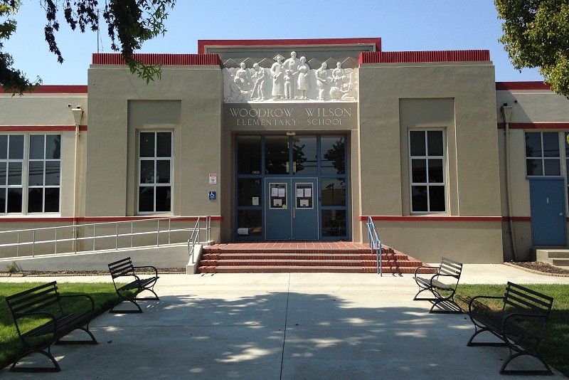 Exterior of Anderson School, beige with red trim, brick steps leading to blue double doors.