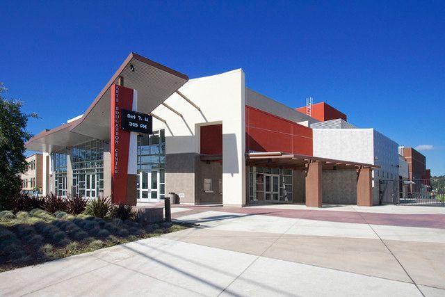 Modern building exterior with glass and red accents against a clear blue sky.