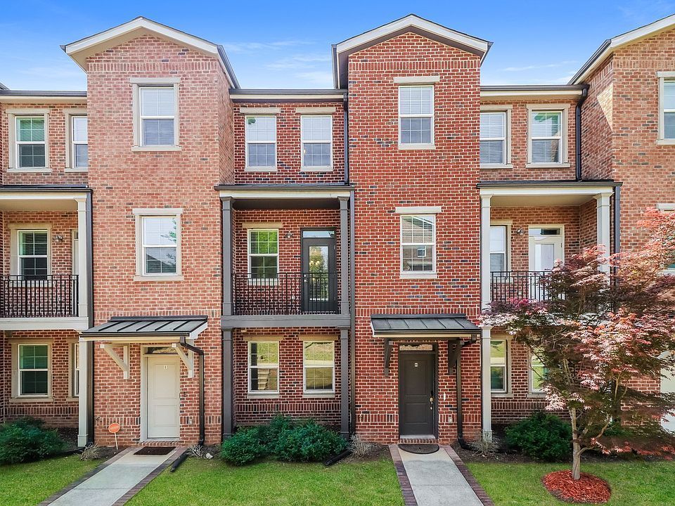 Row of brick townhouses with multiple stories and small front balconies.